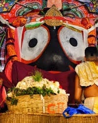Child beside a decorated large-eyed figure with a basket of flowers