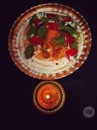 A lit candle beside a plate, featured in the Bali Trutiya article